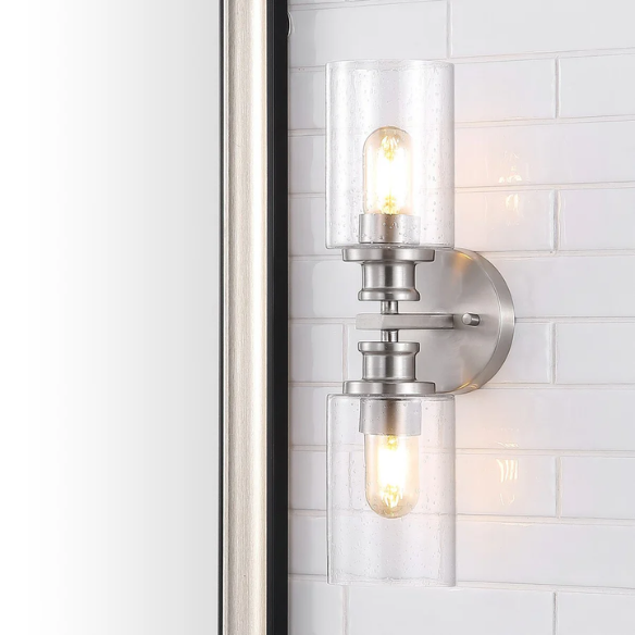 Brushed nickel wall sconce with two clear seeded glass cylinder shades and Edison-style LED bulbs, perfect for bathrooms or hallway accent lighting