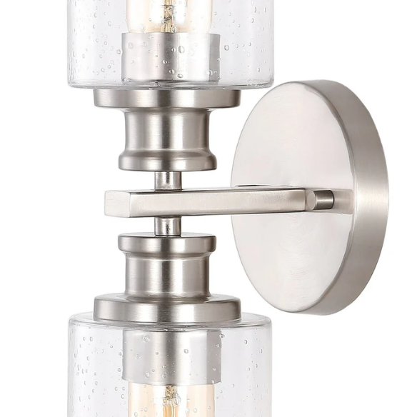 Brushed nickel wall sconce with two clear seeded glass cylinder shades and Edison-style LED bulbs, perfect for bathrooms or hallway accent lighting