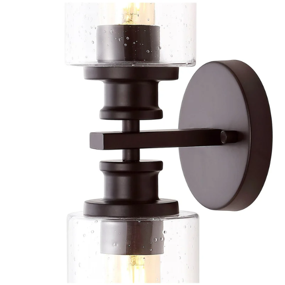 Oil-rubbed bronze wall sconce with dual clear seeded glass cylinder shades and Edison-style LED bulbs, perfect for rustic, farmhouse, or traditional interiors
