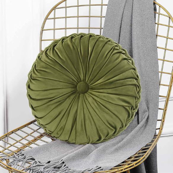 Olive green velvet round throw pillows with hand-pleated detailing and button center, styled on a beige sofa for a warm, inviting look.