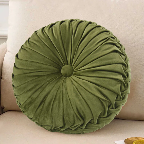 Olive green velvet round throw pillows with hand-pleated detailing and button center, styled on a beige sofa for a warm, inviting look.