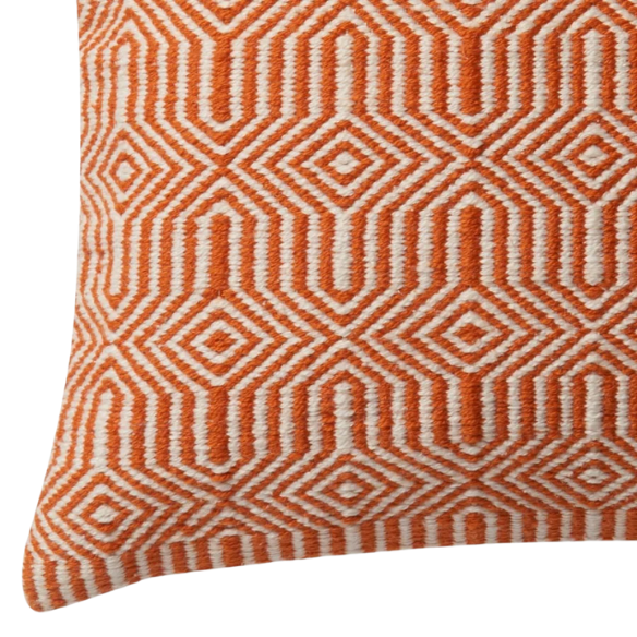 Orange and cream geometric throw pillow on a modern patio chair with bright outdoor decor