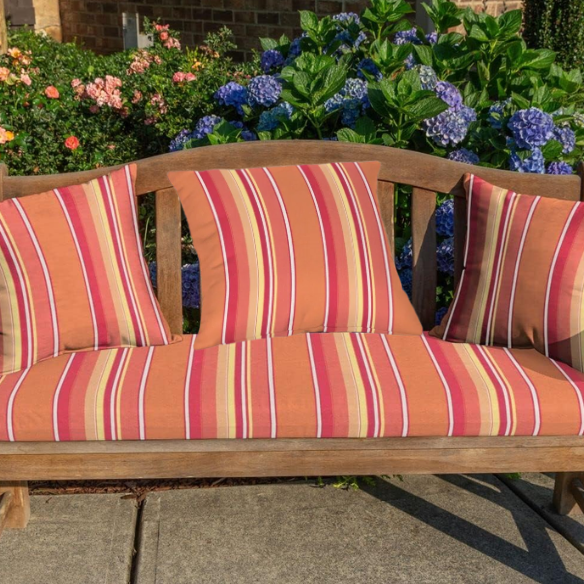 Striped accent pillow in vibrant orange, red, yellow, and white – reversible, weather-resistant, and overstuffed with polyester fill for indoor or outdoor use.