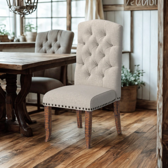 Set of 2 beige button-tufted farmhouse dining chairs with rustic wood legs, nailhead trim, and upholstered linen-like fabric.