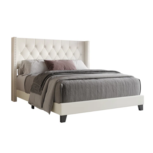 Beige queen-size bed with faux leather upholstery, wingback tufted headboard, nailhead trim, and low-profile wooden frame.