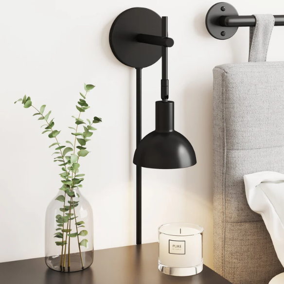 Black plug-in wall sconce with adjustable metal arm and bell-shaped shade, featuring inline on/off switch and matching black cord cover, ideal for task lighting or bedside use.