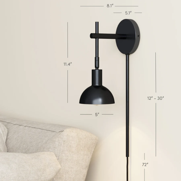 Black plug-in wall sconce with adjustable metal arm and bell-shaped shade, featuring inline on/off switch and matching black cord cover, ideal for task lighting or bedside use.