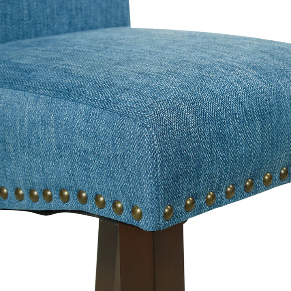 Blue denim upholstered Parsons chair with scrolled back, antique bronze nailhead trim, and solid wood legs