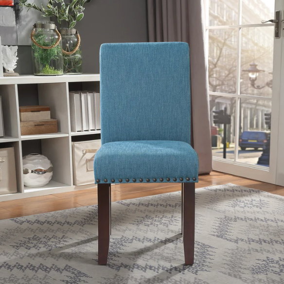 Blue denim upholstered Parsons chair with scrolled back, antique bronze nailhead trim, and solid wood legs