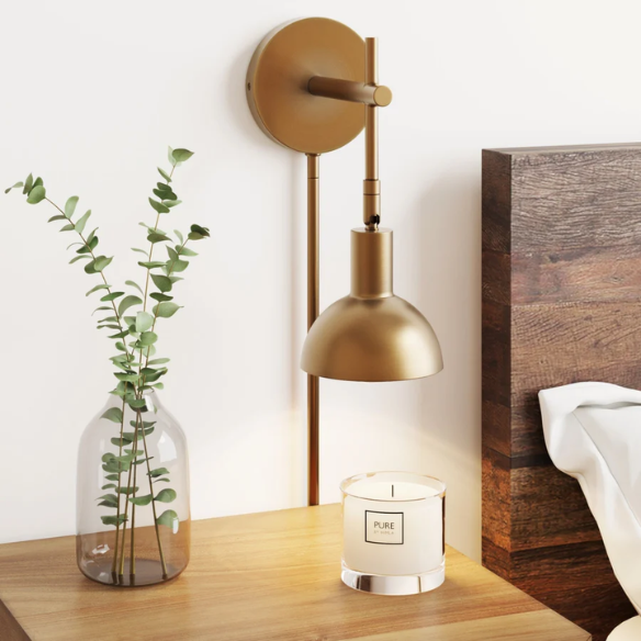 Brass plug-in wall sconce with adjustable swing arm and bell shade, featuring a built-in switch and cord cover for modern bedroom or reading nook lighting