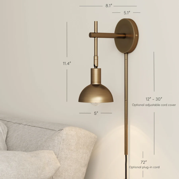 Brass plug-in wall sconce with adjustable swing arm and bell shade, featuring a built-in switch and cord cover for modern bedroom or reading nook lighting