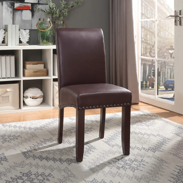Brown faux leather Parsons chair with scrolled back, antique bronze nailhead trim, and solid wood legs