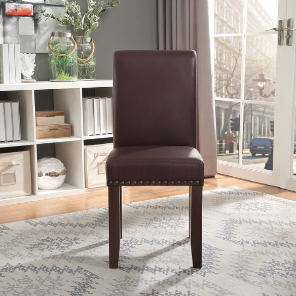 Brown faux leather Parsons chair with scrolled back, antique bronze nailhead trim, and solid wood legs