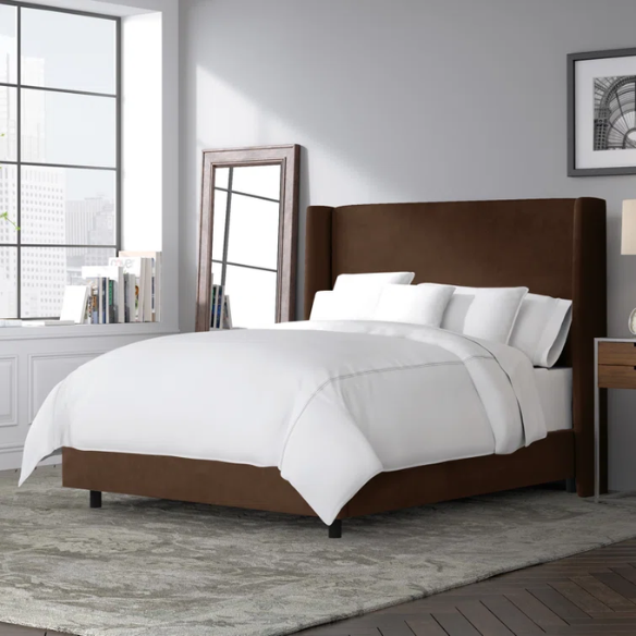 Brown king-size upholstered bed in velvet fabric with wingback headboard and low-profile black metal legs.