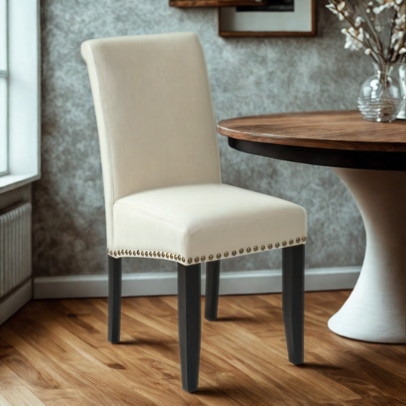 Cream faux leather Parsons chair with scrolled high back, antique bronze nailhead trim, and solid wood legs