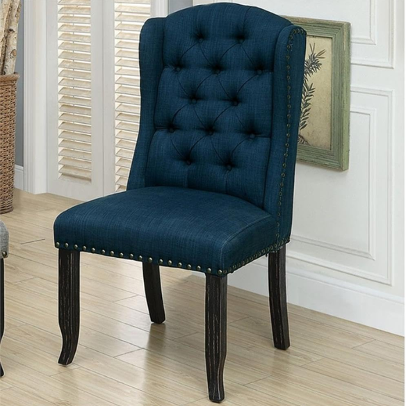 Set of two dark blue upholstered farmhouse dining chairs with tufted backs, brass nailhead trim, and antique black wood legs.