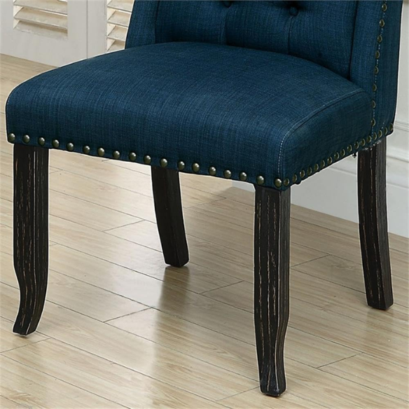 Set of two dark blue upholstered farmhouse dining chairs with tufted backs, brass nailhead trim, and antique black wood legs.