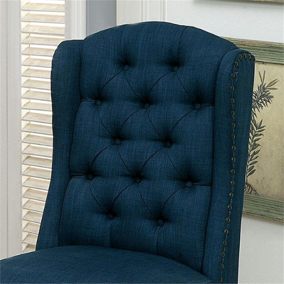 Set of two dark blue upholstered farmhouse dining chairs with tufted backs, brass nailhead trim, and antique black wood legs.