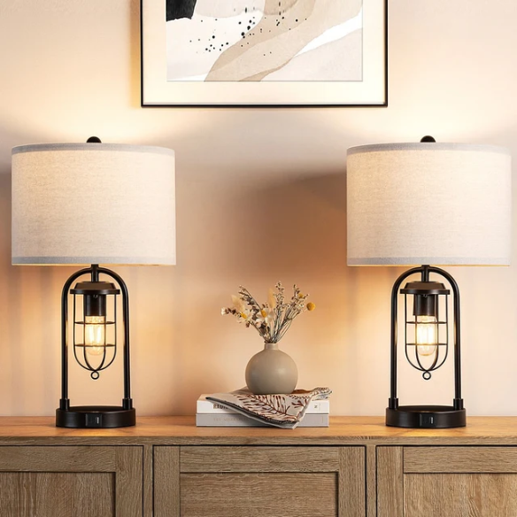 Set of two 21.5-inch espresso table lamps with arch-shaped metal bases, beige fabric drum shades, built-in USB-A and USB-C charging ports, and lantern-style night lights — ideal for modern, industrial, or transitional interiors.