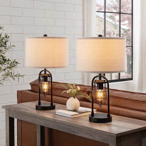 Set of two 21.5-inch espresso table lamps with arch-shaped metal bases, beige fabric drum shades, built-in USB-A and USB-C charging ports, and lantern-style night lights — ideal for modern, industrial, or transitional interiors.