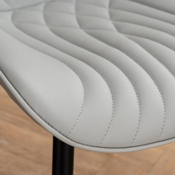 Set of 2 grey faux leather dining chairs with fishtail tufted backs and black metal legs, ideal for modern and minimalist dining room interiors.