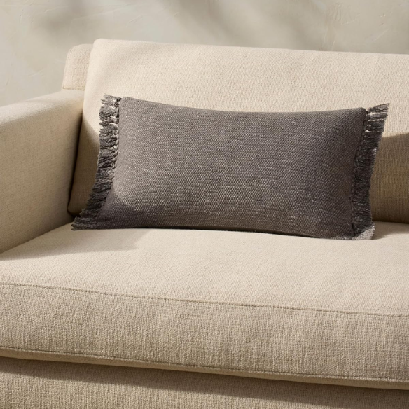 Grey rectangular lumbar throw pillow with fringe trim, 13x21 inches, featuring a cotton-polyester-rayon cover and plush polyester fill—perfect for modern and neutral interior décor.