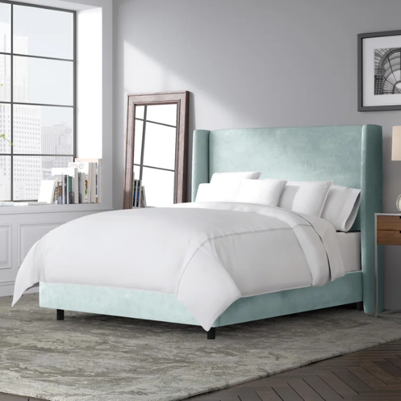 Light aqua king-size upholstered bed in velvet fabric with wingback headboard and low-profile black metal legs.