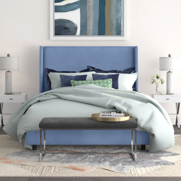 Light denim blue king-size upholstered bed in linen fabric with wingback headboard and low-profile black metal legs.