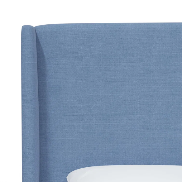 Light denim blue king-size upholstered bed in linen fabric with wingback headboard and low-profile black metal legs.