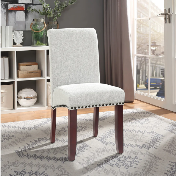 Light grey upholstered Parsons chair with scrolled high back, antique bronze nailhead trim, and solid wood legs