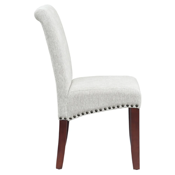 Light grey upholstered Parsons chair with scrolled high back, antique bronze nailhead trim, and solid wood legs