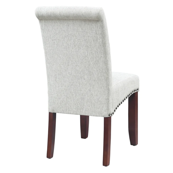 Light grey upholstered Parsons chair with scrolled high back, antique bronze nailhead trim, and solid wood legs