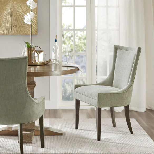 Set of 2 upholstered armless dining chairs in muted green with solid wood legs, high backrest, and elegant piping detail.