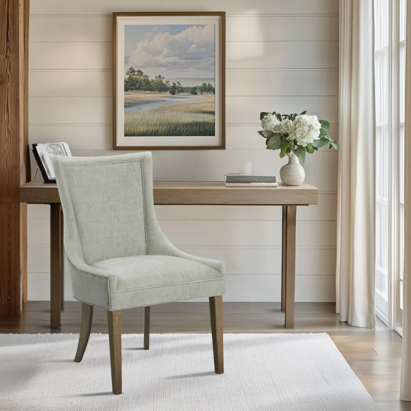Set of 2 upholstered armless dining chairs in muted green with solid wood legs, high backrest, and elegant piping detail.