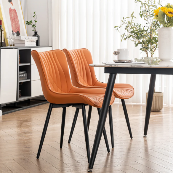 Set of 2 orange faux leather dining chairs with fishtail tufted backs and black metal legs, perfect for modern and colorful dining room settings.