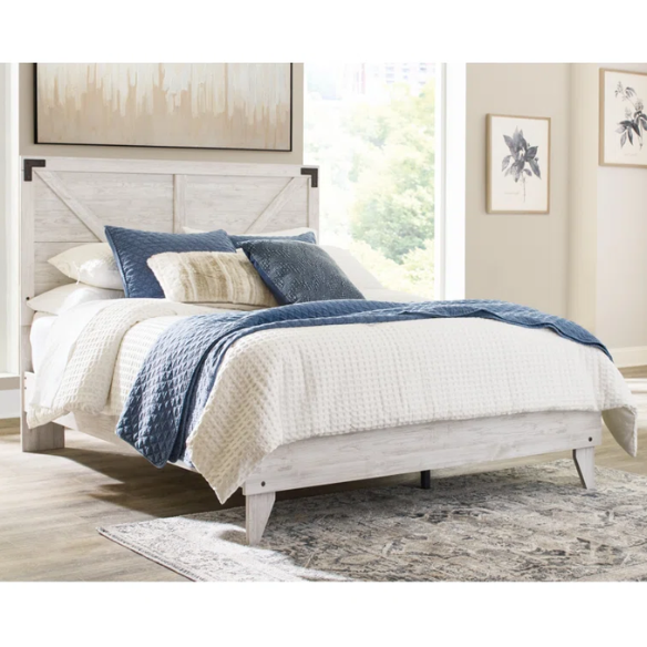 Rustic white platform bed with a distressed finish, crossbuck headboard, and metal support slats, styled in a cozy farmhouse bedroom.