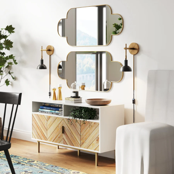 Set of two black and brass plug-in wall sconces with adjustable swing arms and brass bell-shaped shades, featuring on/off cord switch and matching black cord covers