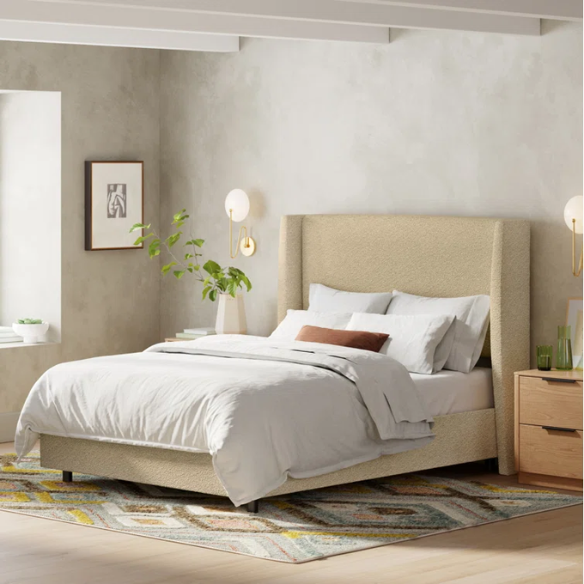 Tan king-size upholstered bed in bouclé fabric with wingback headboard and low-profile black metal legs.