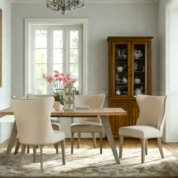 Set of two cream upholstered dining chairs with curved wingback design, dark pewter nailhead trim, and latte wood legs in a traditional style