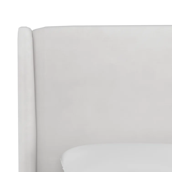 White king-size upholstered bed in velvet fabric with wingback headboard and low-profile black metal legs.