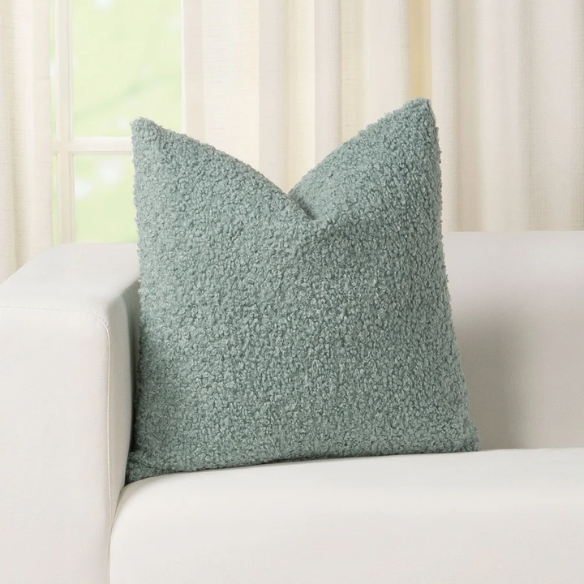 Seafoam green bouclé throw pillow with soft looped texture, square accent pillow on a neutral sofa