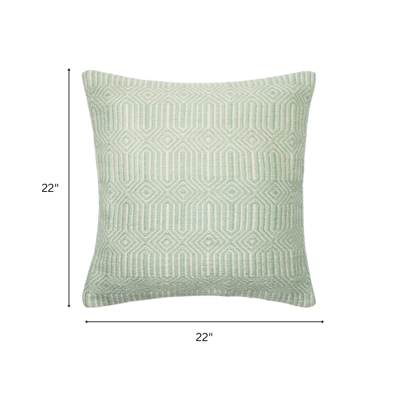 Seafoam green and cream geometric throw pillow on an outdoor patio chair with modern decor