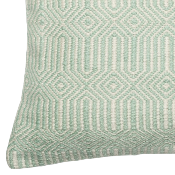 Seafoam green and cream geometric throw pillow on an outdoor patio chair with modern decor