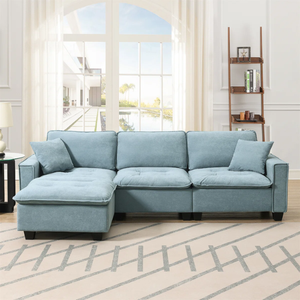 Tranquil sea blue suede L-shaped sectional sofa with tufted seat cushions, reversible chaise, removable ottoman, and two matching throw pillows