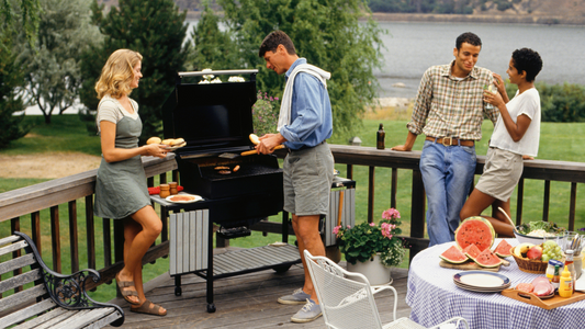 In a vibrant outdoor setting, a cheerful couple is gathered near a sizzling grill, enjoying a sunny day.