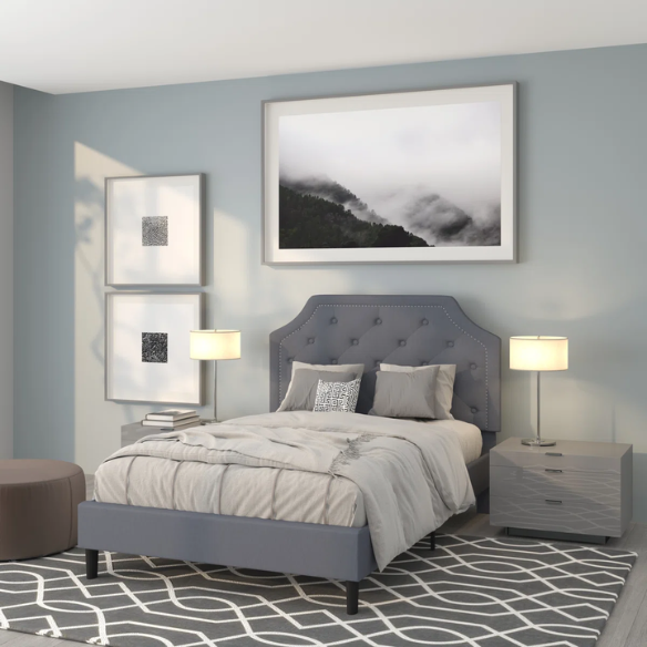 Modern bedroom with gray upholstered bed, nightstands, and wall art.