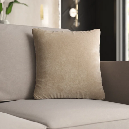 Sand crushed velvet throw pillow, 16x16 square with soft reversible fabric and hidden zipper, styled in a cozy, neutral-toned living space.

