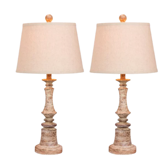 Set of two 26.5-inch candlestick-style resin table lamps in distressed antique beige with oatmeal fabric drum shades, ideal for farmhouse or traditional interiors
