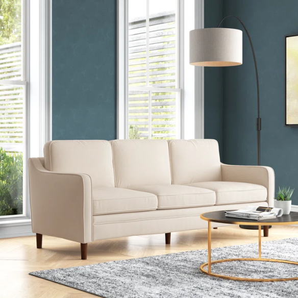 Beige chenille upholstered sofa with curved track arms, loose back cushions, and brown tapered wood legs, in a mid-century modern design.