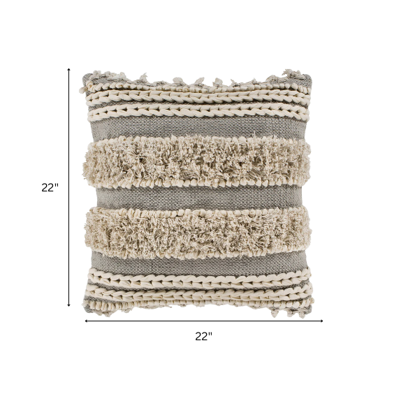 Beige and cream boho accent pillow with tassels and striped texture on a cozy neutral-toned sofa

